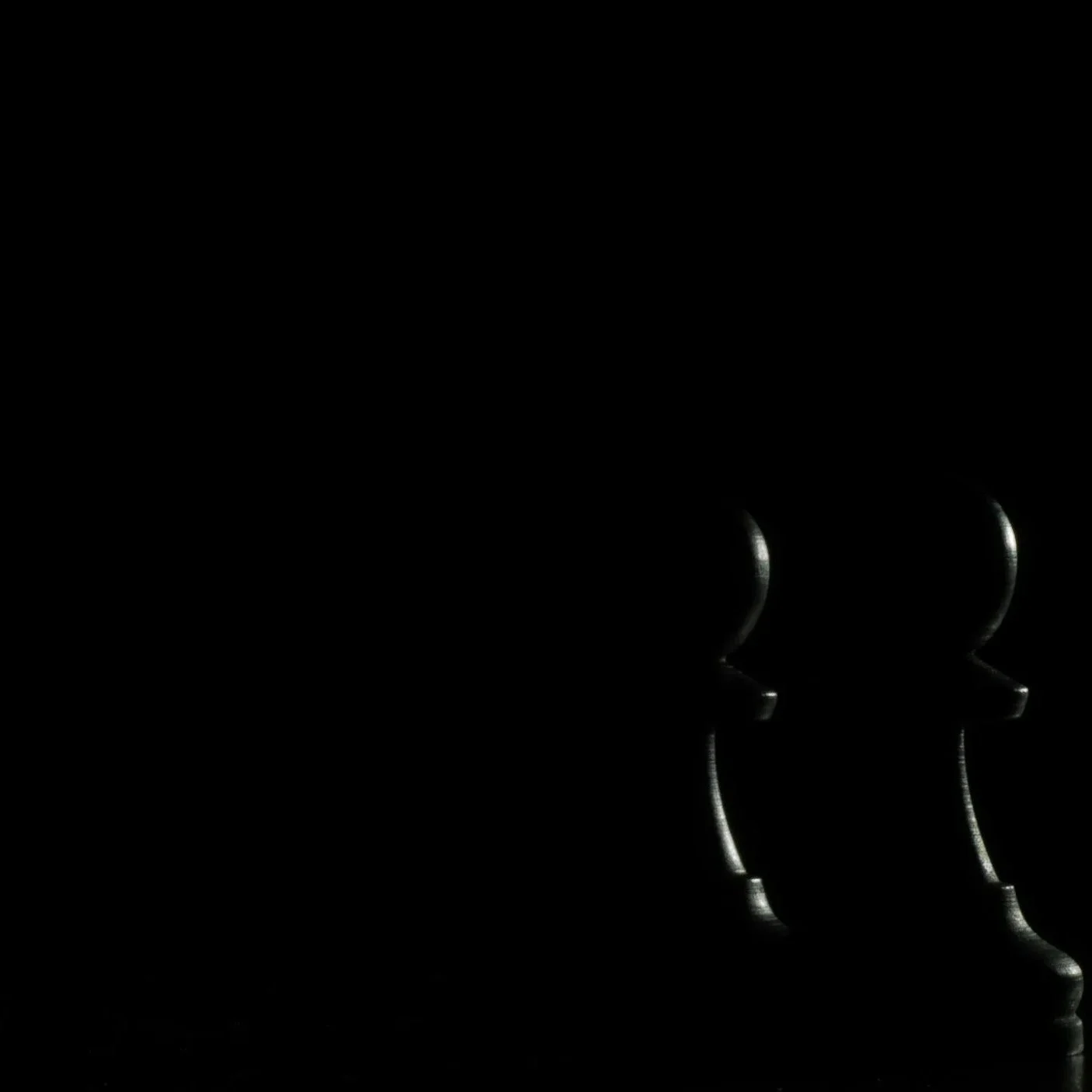 Dark chess pieces against a black background