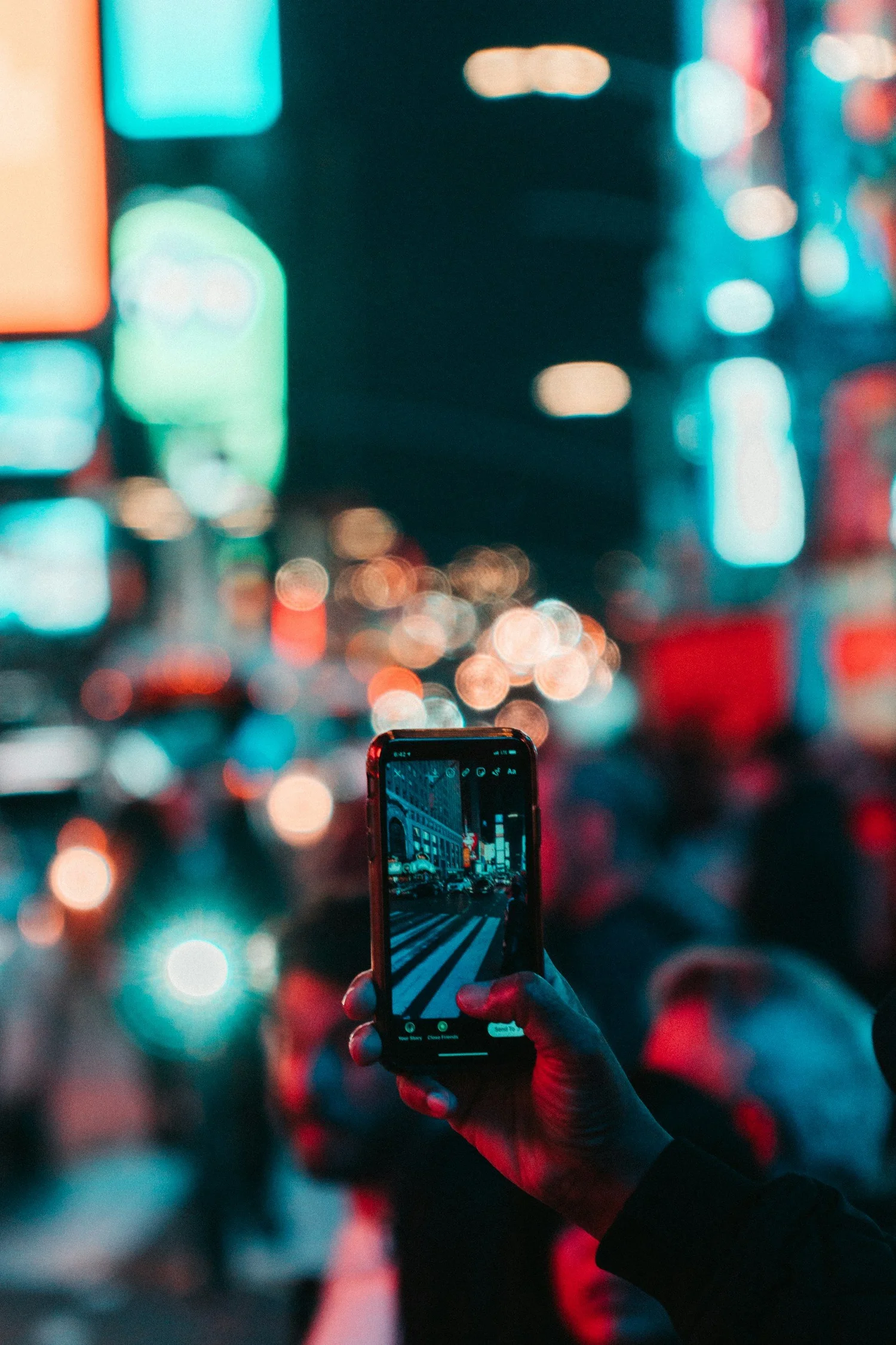 A phone photographing a brightly lit city at night