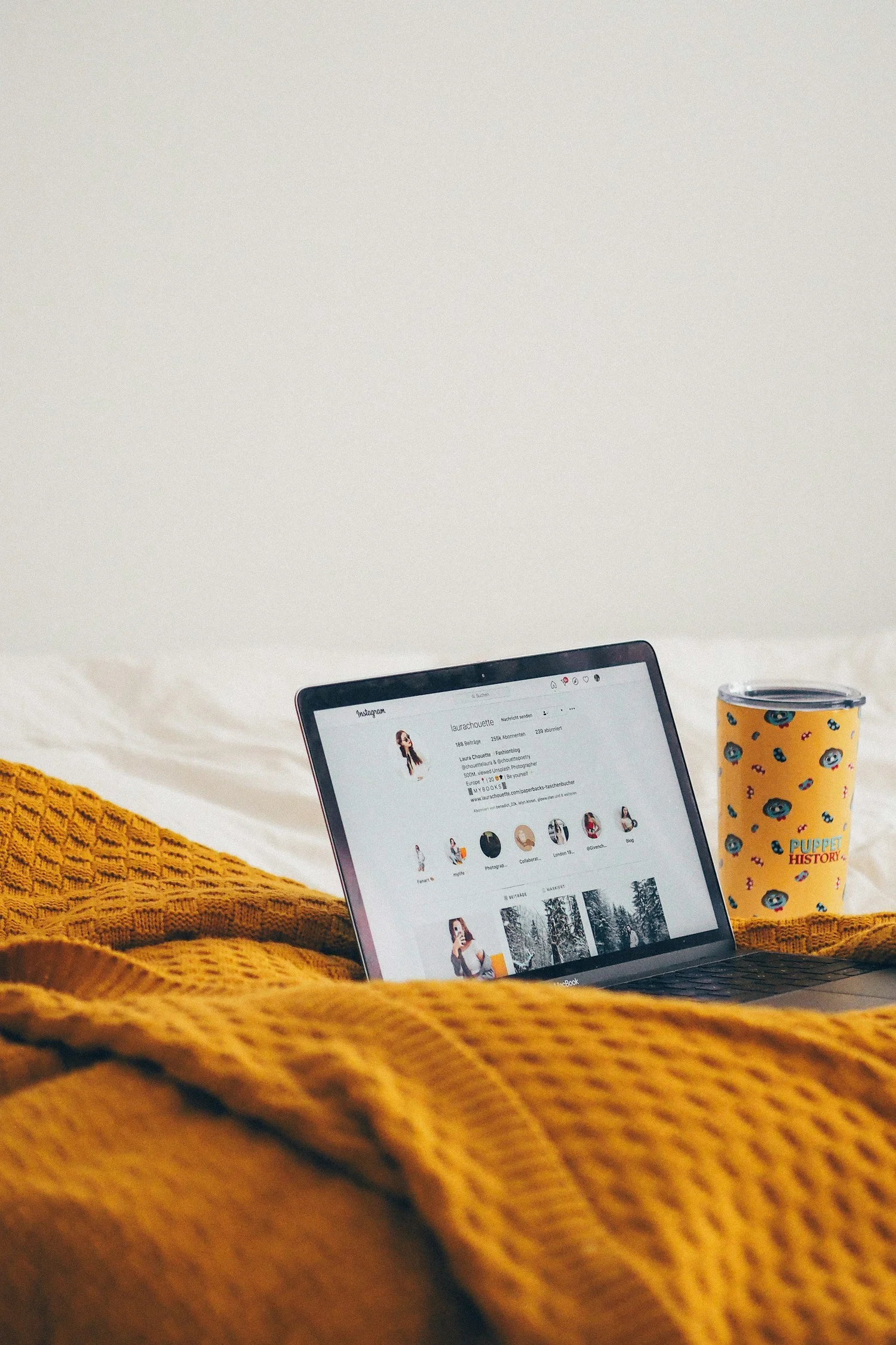 Social media displayed on a laptop beside a yellow cup